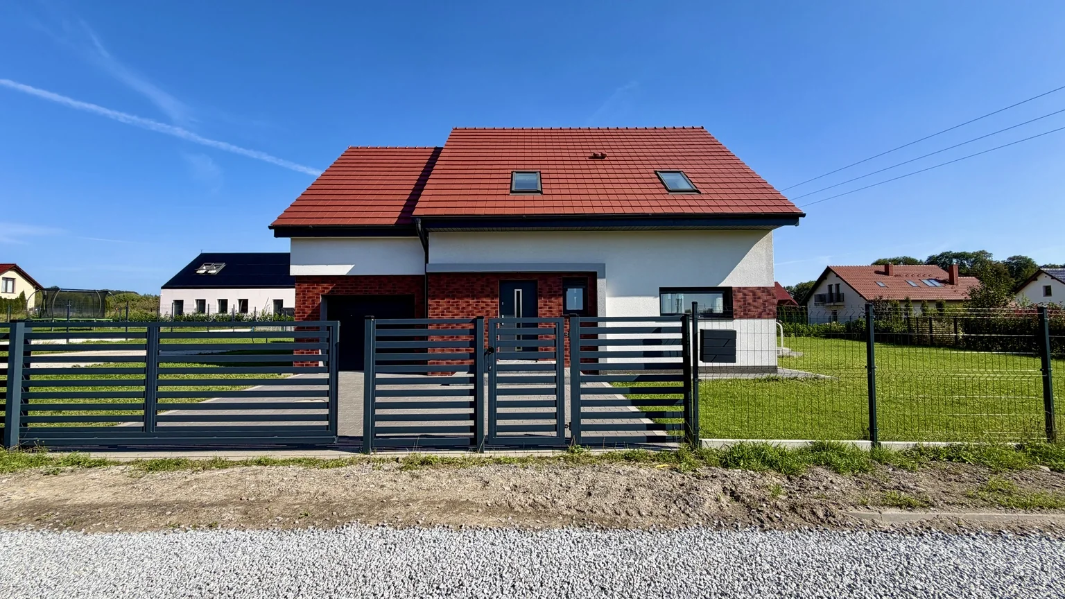 Front domu wolnostojącego w Wiszni Małej z ogrodzeniem i podjazdem